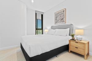 a white bedroom with a large bed and a table at Stylish 2-Bed Unit with Views & Rooftop Access in North Fremantle