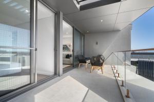 a room with sliding glass doors and a staircase with chairs at Penthouse Stay With Ocean Views in North Fremantle +30 photos