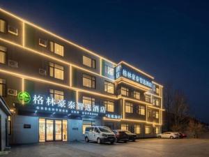 a building with cars parked in a parking lot at night at GreenTree Inn Express Qingdao Jiaodong International Airport in Qingdao