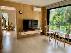 a living room with a television and a table and chairs at Sogil inner Forest in Jeju