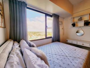 a large bed in a bedroom with a large window at Preum Properties Tagaytay in Tagaytay