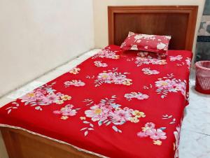 a bed with a red bedspread with flowers on it at Hotel Guest House Saydabad in Dhaka