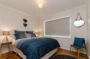 a bedroom with a bed and a window and a chair at Penguin Beach House in Penguin