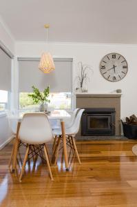 een eetkamer met een tafel, stoelen en een klok bij Penguin Beach House in Penguin