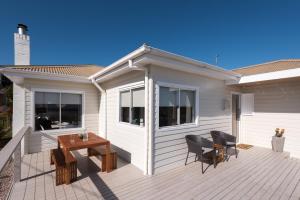 a house with a deck with a table and chairs at Penguin Beach House in Penguin