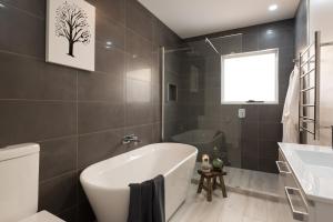 een badkamer met een wit bad en een boomafbeelding aan de muur bij Penguin Beach House in Penguin +13 foto's