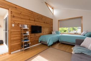 a bedroom with two beds and a wall with wood at Penguin Beach House in Penguin