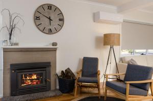 een woonkamer met een open haard en een klok aan de muur bij Penguin Beach House in Penguin