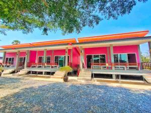 ein rosafarbenes Gebäude mit Bänken davor in der Unterkunft Kwanjai Resort in Chanthaburi
