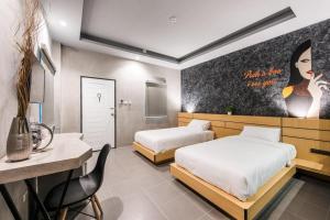 a bedroom with two beds and a table and a desk at Hide & Seek Resort Krabi in Ban Khlong Chi Lat