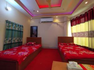 two beds in a room with red sheets at Hotel Guest House Saydabad in Dhaka