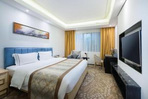 ein Hotelzimmer mit einem großen Bett und einem Flachbildfernseher in der Unterkunft Golden Central Hotel Shenzhen in Shenzhen