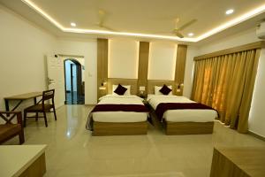 a hotel room with two beds and a table at North Fort Regency in Cochin