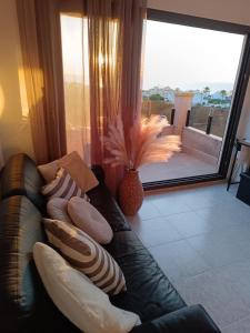 un sofá de cuero negro en una sala de estar con una gran ventana en Rising Sun Bungalow, en Torrevieja
