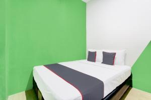 een bed in een kamer met groene en witte muren bij Hotel O Yogyakarta near Jalan Malioboro formerly Malio Inn in Yogyakarta
