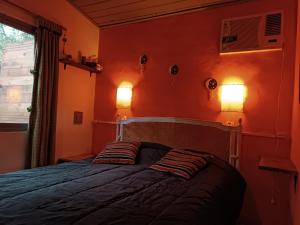 a bedroom with orange walls and a bed with two pillows at Samadhi in Tigre