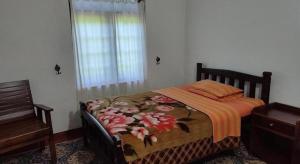 a bedroom with a bed with a floral bedspread at St. Andrews Hostel in Nuwara Eliya