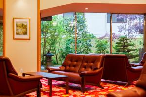 a waiting room with a leather couch and chairs at BeppuOnsen Hotel Sansenkaku in Beppu