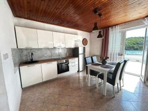 a kitchen with white cabinets and a table and chairs at Kuki Appartements Rab in Supetarska Draga