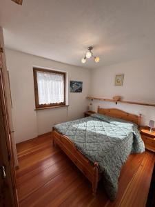 a bedroom with a bed and a window and wooden floors at Casa Gatto in Auronzo di Cadore