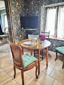 a dining room with a table and chairs and a tv at les hortensias La Souris Des Champs in Étival-Clairefontaine