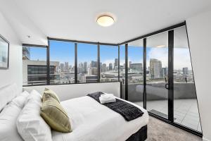 a bedroom with a white bed and large windows at Docklands Private Collection - NEWQUAY in Melbourne +37 photos