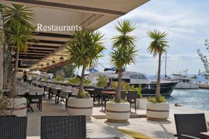 a restaurant with palm trees and a boat in the water at APARTMENTS KING 2 in Podstrana