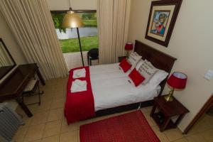 ein Schlafzimmer mit einem Bett mit roten Kissen in der Unterkunft Forellenhof Guest Farm in Wakkerstroom