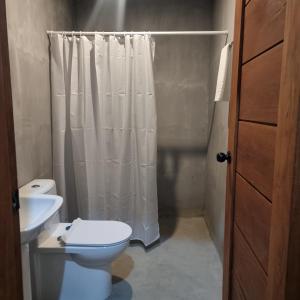 ein Badezimmer mit Toilette und Duschvorhang in der Unterkunft Mulawin B&B in El Nido