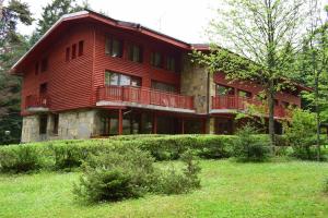 Cette grande maison rouge possède un balcon sur une colline. dans l'établissement Хотел "Калина", à Borovets
