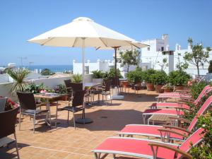 
a patio area with tables, chairs and umbrellas at Almadraba Conil in Conil de la Frontera
