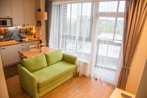 eine grüne Couch in einer Küche mit einem großen Fenster in der Unterkunft Sky Studio near the Vilnius Center in Vilnius