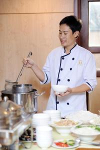 a woman in a kitchen holding a bowl at Hoang Yen 2 Hotel in Thu Dau Mot