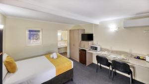a hotel room with a bed and a kitchen at Biloela Centre Motel & Grevillea Steakhouse & Bar in Biloela