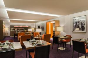 a restaurant with tables and chairs and a fireplace at Hôtel le Derby Alma by Inwood Hotels in Paris