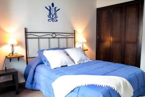 1 dormitorio con 1 cama azul y blanca y 2 lámparas en Apartamento Senderos de Hervas, en Hervás