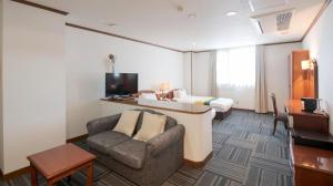 a hotel room with a bed and a couch and a chair at Hotel New Palace Aizuwakamatsu in Nukazuka