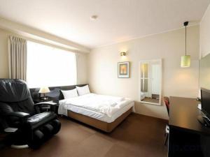 a hotel room with a bed and a chair at Hotel The Grand Court Matsusaka in Tsu