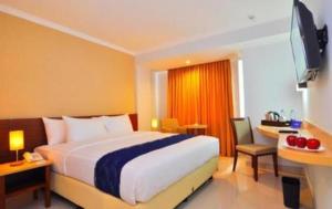 a bedroom with a bed and a desk and a television at Bogor Valley Hotel in Kalibata 1