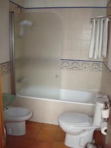 
a white toilet sitting next to a bath tub in a bathroom at Almadraba Conil in Conil de la Frontera
