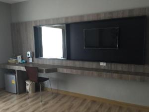 ein Zimmer mit einem Schreibtisch mit Fernseher und einem Stuhl in der Unterkunft Hotel Le Lerts Living in Khon Kaen