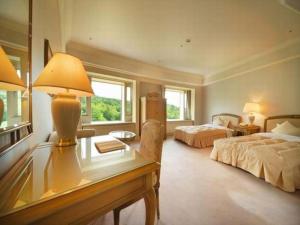 a bedroom with two beds and a desk with a lamp at Hotel de Premiere Minowa in Inawashiro