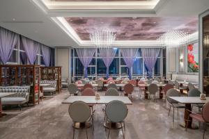 a dining room with tables and chairs and windows at Mercure Guangzhou Financial City in Guangzhou