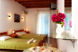 a room with two beds and a vase with flowers in it at Sotiria in Paramonas