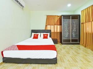 a bedroom with a large bed with red pillows at OYO 90315 Chalet Pantai Rantau Panjang in Kampong Kandang +42 photos