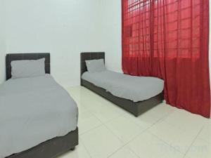 two beds in a room with red curtains at OYO HOME 90646 Casaria Paka Homestay in Paka