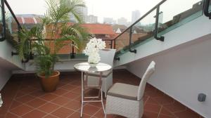a small table and chairs on a balcony with plants at Heeren Straits Hotel in Malacca