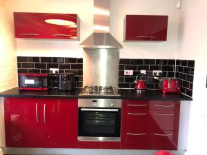 a kitchen with red cabinets and a stove at Cozy Sheffield Guest Room with Shared Facilities in Sheffield +7 photos