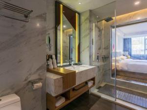 ein Badezimmer mit Waschbecken und großem Spiegel in der Unterkunft Borrman Hotel Hechi Bama Central Cultural Plaza in Bama + 117 Fotos