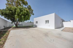 ein weißes Gebäude mit einem Baum davor in der Unterkunft Casa de la Noria in Chiclana de la Frontera